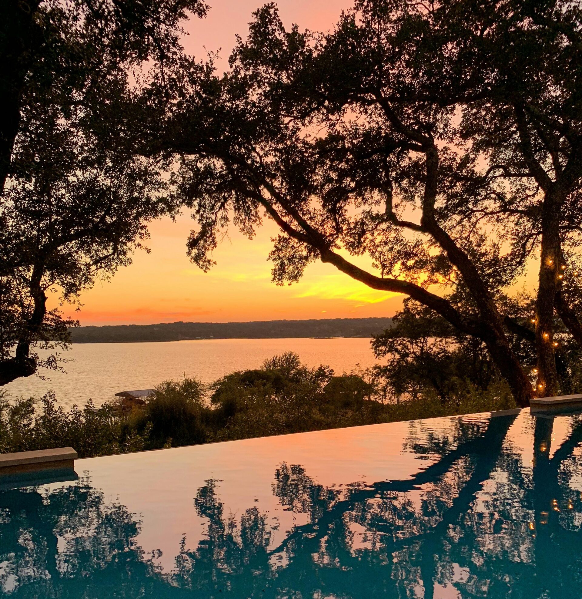 Sunset over lake behind trees.